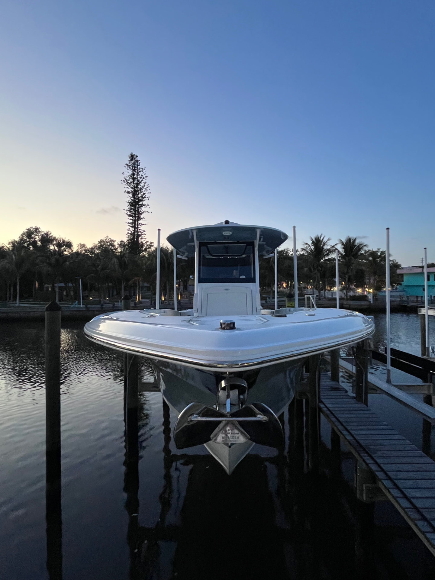 Center console held on a lift at a private dock at dusk, hull polished and reflecting the water