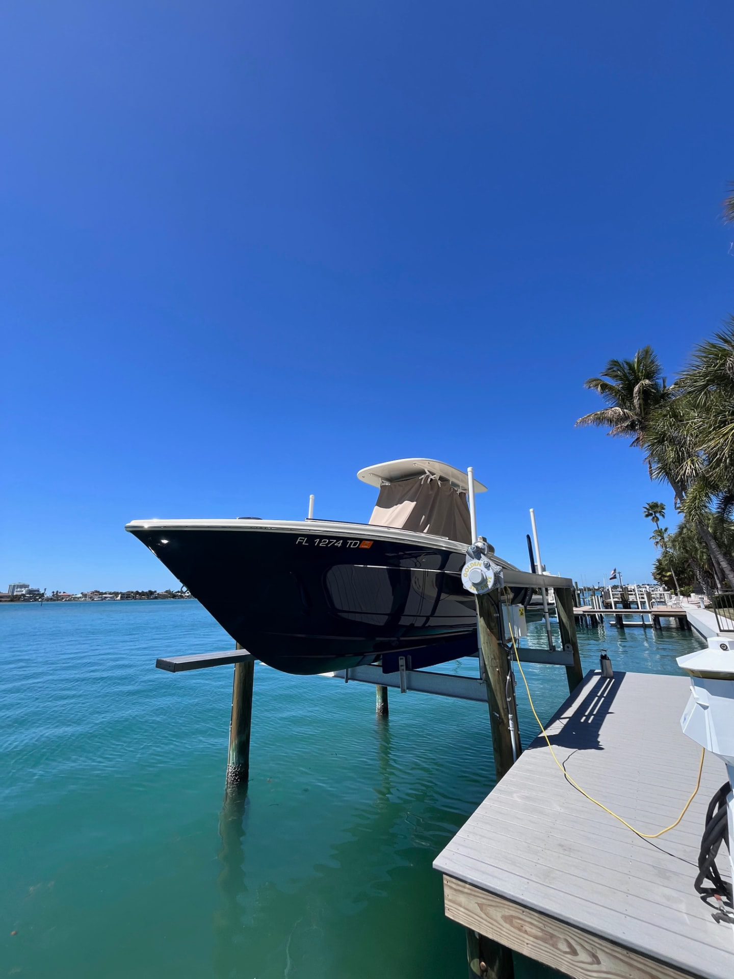 Center console on a lift over clear turquoise water on the Intracoastal, palms along the shoreline